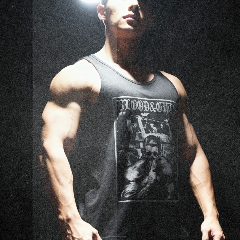 Model wearing Most Natty Blood & Guts bodybuilding tank top showing relaxed standard fit in moody setting