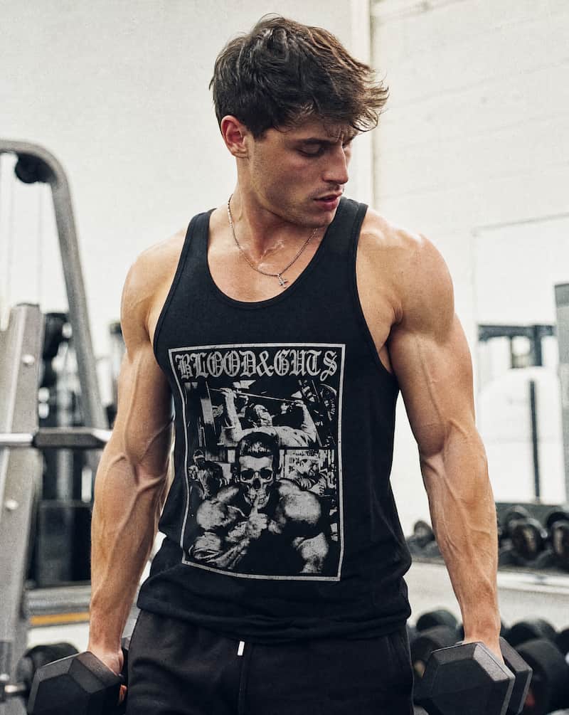 Man in gym holding dumbbells wearing Blood & Guts Tank Top