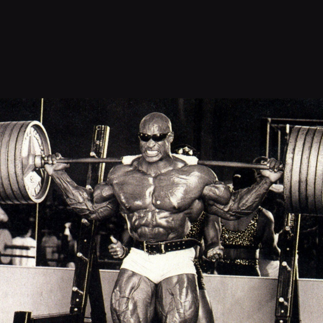 Ronnie Coleman squatting massive barbell with sunglass on.