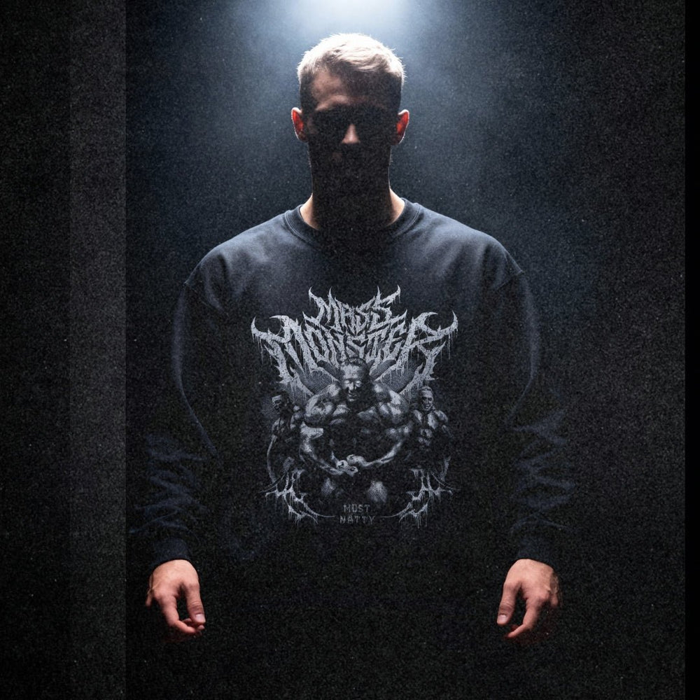 Model wearing Markus Ruhl Mass Monster bodybuilding pump cover crewneck in dark moody gym setting with dramatic lighting